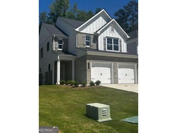 Charming two-story home boasts brick accents, gray shutters, a well-manicured lawn, and a two-car garage at 1151 Park Center Nw Cir, Austell, GA 30168