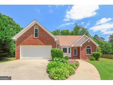 Charming brick home featuring an attached garage, manicured landscaping, and a curved walkway leading to the entrance at 3533 Saddlebrook Dr, Loganville, GA 30052