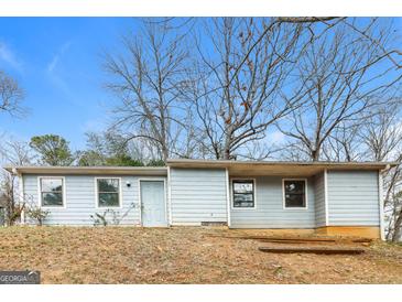 Exterior view of a one-story home with light blue siding and bare trees against a blue sky at 8005 Big Rock Dr, Douglasville, GA 30134