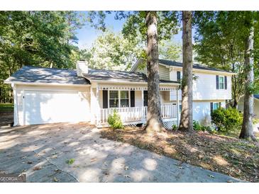 Charming two-story home with white exterior, front porch, attached garage and mature trees at 2730 Pine Log Way, Buford, GA 30519