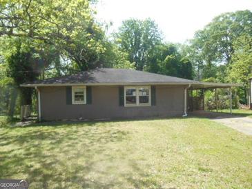 Cozy single-story home with a covered carport nestled among mature trees and a well-maintained lawn at 1391 Peachcrest Rd, Decatur, GA 30032