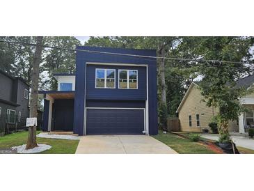 Striking modern home features a beautiful blue exterior, a garage, and lovely green lawn at 1378 Gus Thornhill Jr Dr, East Point, GA 30344