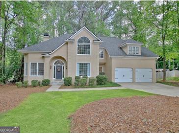 Charming beige two-story home featuring an attached two-car garage and a well-manicured front lawn at 302 Welton Way, Peachtree City, GA 30269