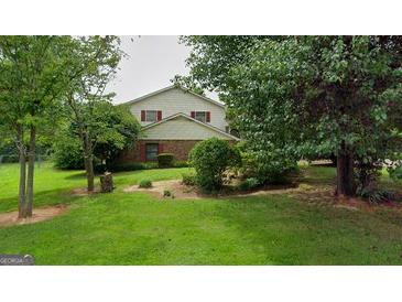 Charming two-story home featuring a lush, green lawn and mature trees in a serene, residential setting at 7369 Aubrey Dr, Riverdale, GA 30296