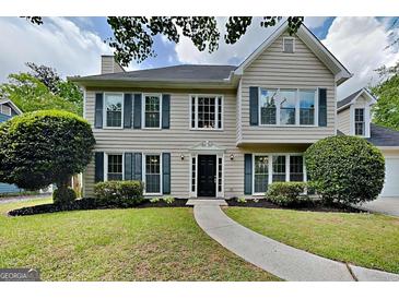 Charming two-story home with a landscaped yard, black shutters and a curved walkway leading to the front door at 1311 Bustling Sw Ln, Marietta, GA 30064