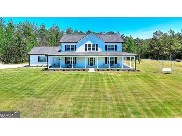 Inviting two-story home with a large front porch and expansive lawn and a swing in the yard at 1621 Dixie Rd, Covington, GA 30014