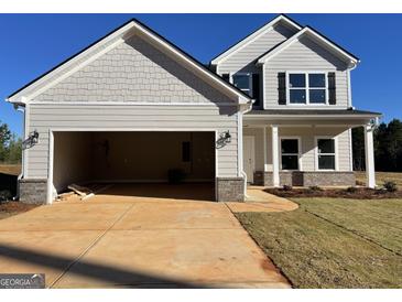 Two-story home with a large garage, gray siding, and a manicured lawn at 715 Colvin Dr, Locust Grove, GA 30248