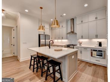 Bright white kitchen features a large island with seating and modern stainless steel appliances and fixtures at 1006 Fendley St, Woodstock, GA 30188