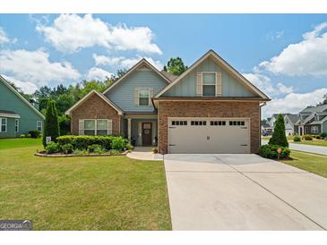 Charming home featuring stone and blue siding, a well-manicured lawn, and an attached two-car garage at 207 Brookstone Dr, Carrollton, GA 30116