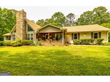 Charming home featuring a stone chimney, inviting front porch, and well-maintained landscaping at 130 Brooklet Way, Brooks, GA 30205