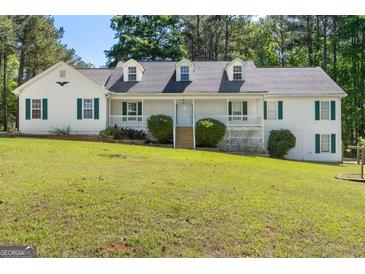 Charming two-story home featuring a covered porch and a well-manicured front yard and mature trees at 3499 S Ola Rd, Locust Grove, GA 30248