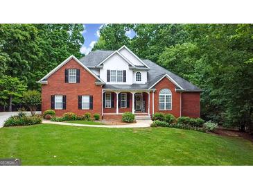 Charming two-story red brick home with lush green lawn, mature trees, and manicured landscaping at 119 Crown Springs Dr, Mcdonough, GA 30252