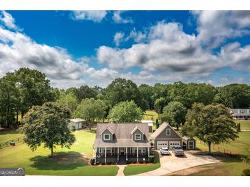 A charming home with a lush green lawn and mature trees under a partly cloudy blue sky at 411 Hampton Rd, Fayetteville, GA 30215