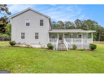 Charming gray home with a welcoming white porch, complemented by a lush green lawn and mature trees at 1125 Babbs Mill Rd, Hampton, GA 30228
