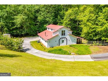 Charming two-story home with a red roof, set amidst a lush green lawn and surrounding trees at 3258 South Mckoy Rd, Villa Rica, GA 30180
