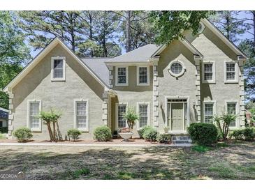 Charming front exterior features light stucco, multi-pane windows, and a meticulously landscaped front yard at 121 Tamerlane, Peachtree City, GA 30269