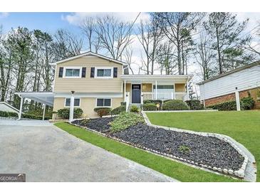 Charming two-story home with manicured lawn and attached carport offers inviting curb appeal at 815 Magna Carta Nw Dr, Atlanta, GA 30318
