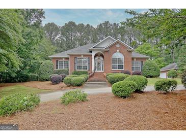 Charming brick home featuring lush landscaping and a well-manicured front yard at 120 Hamilton Glen Ct, Fayetteville, GA 30215