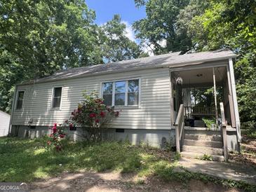 Cozy home with a covered front porch, surrounded by lush greenery and accented by blooming red roses at 530 Whitley Dr, Forest Park, GA 30297