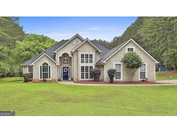 Stunning two-story home with a well-manicured lawn, decorative shrubbery, and a blue front door at 391 Massengale Rd, Brooks, GA 30205