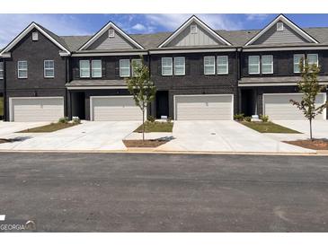 New townhome construction showcasing brick facades, attached garages, and manicured lawns at 240 Epping Drive, Stockbridge, GA 30281