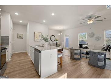 Bright living room with ceiling fan, white sofa, and two stylish gray chairs at 240 Epping Drive, Stockbridge, GA 30281