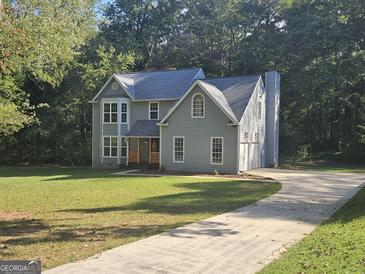 Charming two-story home featuring a manicured lawn and a long driveway, surrounded by lush trees at 150 Park Timbers Drive, Sharpsburg, GA 30277
