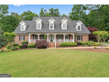 Charming brick home featuring a welcoming front porch, complemented by beautifully landscaped grounds and lush greenery at 510 Jenna Trl, Mcdonough, GA 30252