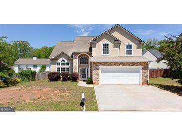 Charming two-story home with a stone veneer and a well-manicured front yard under a clear blue sky at 2805 Topaz Rd, Riverdale, GA 30296