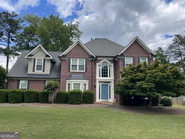 Charming brick home with a well-manicured lawn, blue front door, and classic architectural details at 840 Yosemite Dr, Suwanee, GA 30024
