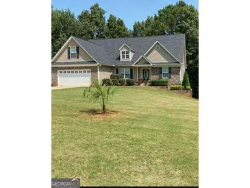Charming home featuring a two car garage, stone accents, and a well maintained lawn at 565 Miles Ct, Locust Grove, GA 30248