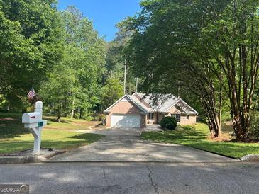 Charming brick home features an attached garage, well-manicured lawn, and a long driveway, nestled amongst mature trees at 4333 Deer Ridge Ct, Lilburn, GA 30047