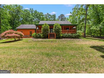 Charming home exterior with a cozy porch, lush greenery, and well-manicured lawn at 3313 Henson Ln, Stockbridge, GA 30281