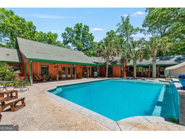 A beautiful in-ground pool with patio, pool-side bar, and wooden home exterior surrounded by mature trees at 3313 Henson Ln, Stockbridge, GA 30281