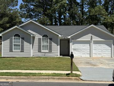 Charming one-story home features a two-car garage, symmetrical arched windows, and neutral gray siding at 6372 Stonebridge Creek Ln, Lithonia, GA 30058