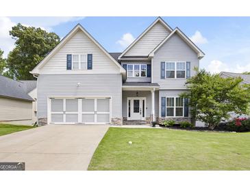 Charming two-story home featuring light gray siding, a well-manicured lawn, and a two-car garage at 1016 Buckeye Ln, Villa Rica, GA 30180