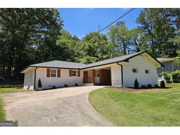 Charming brick home with a circular driveway, manicured lawn, and lush greenery, offering a welcoming curb appeal at 1939 Sandringham Sw Dr, Atlanta, GA 30311