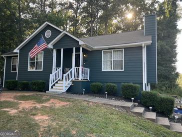Charming single-Gathering home featuring a cozy front porch, well-kept landscaping, and an American flag at 150 Doe Run Ct, Sharpsburg, GA 30277