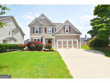 Two-story home with manicured lawn, brick accents, a two-car garage, and attractive landscaping at 613 Blackburn Ln, Peachtree City, GA 30269