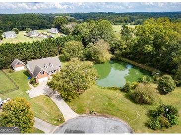Stunning aerial view of home with a pond and lush greenery in a serene, private setting at 557 Arrowhead Cir, Rutledge, GA 30663