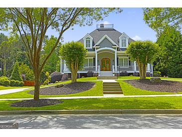 Stunning home featuring a manicured lawn, charming front porch, and lush landscaping at 405 Highgrove Dr, Fayetteville, GA 30215