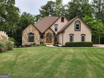 Charming home featuring stone accents, a manicured lawn, and a well-maintained landscape design at 3110 Birchton St, Johns Creek, GA 30022