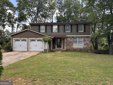 Charming two-story home with a two-car garage and stone accents in a well-maintained lawn at 1055 Worthington Hills Dr, Roswell, GA 30076