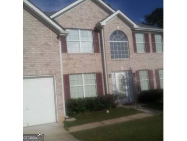 Two-story brick home featuring an attached garage, a manicured lawn, and large windows at 11950 Markham Way, Hampton, GA 30228