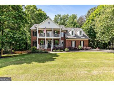 Elegant brick home with a two-story porch, landscaped yard, and mature trees at 218 Woodruff Way, Peachtree City, GA 30269