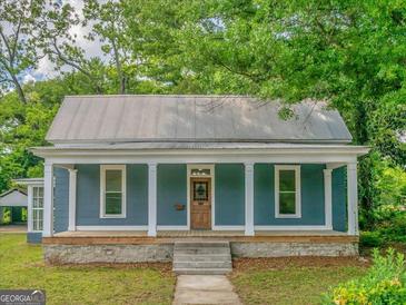 Charming single-story home with a welcoming front porch and a classic metal roof at 1128 Milstead Ne Ave, Conyers, GA 30012