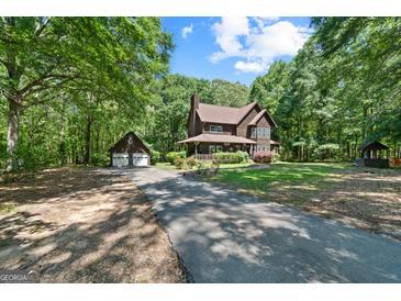 Inviting two-story home with a long driveway and a detached two-car garage nestled in a lush, wooded lot at 1627 Leguin Mill Rd, Locust Grove, GA 30248