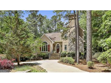 Charming home exterior featuring a stone chimney, stucco facade, and lush landscaping at 100 Rosemont, Peachtree City, GA 30269