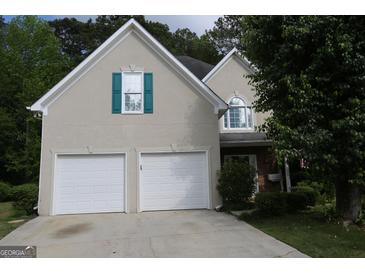 Charming home with a two-car garage, neutral stucco, and unique teal window shutters at 235 Woodstream Way, Fayetteville, GA 30214