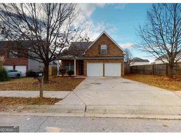 Charming two-story home featuring a brick facade, double garage, and well-maintained front yard at 1871 Sandy Trail Dr, Hampton, GA 30228